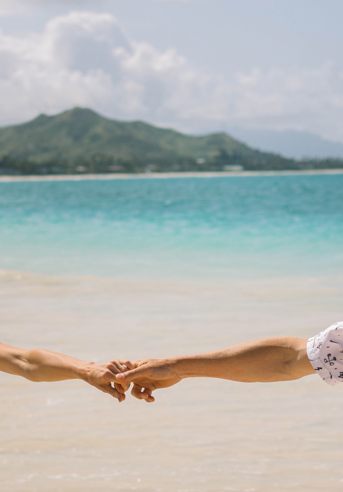 Bride and groom holding hands on an Oahu beach