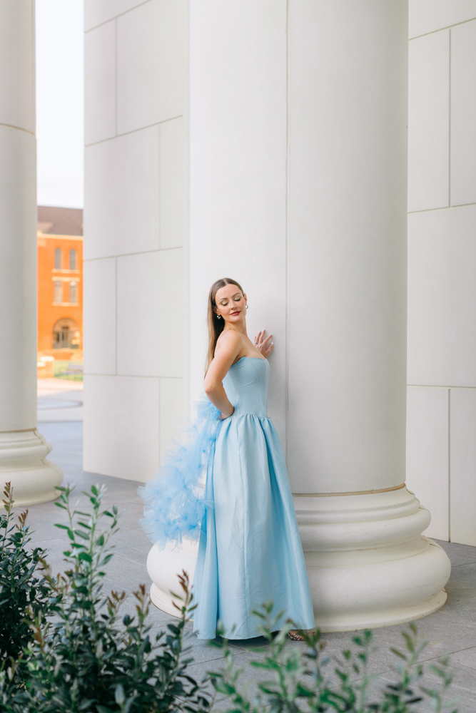 Bride in blue gown posing against courthouse column